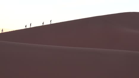 Hikers-ascend-a-massive-sand-dune-at-Namib-Naukluft-National-Park-in-the-Nam-desert-Namibia