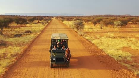 Antenne-Eines-Safari-Jeeps,-Der-Auf-Den-Ebenen-Afrikas-Im-Erindi-Wildreservat-In-Namibia-Reist,-Mit-Einheimischem-San-Tribal-Spotter-Führer,-Der-Auf-Der-Vorderseite-Sitzt-Und-Wildtiere-Beobachtet-2