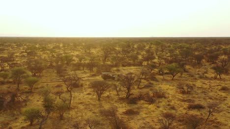 Ausgezeichnete-Antenne-Eines-Safari-Jeeps,-Der-Auf-Den-Ebenen-Afrikas-Im-Erindi-Wildreservat-In-Namibia-Reist,-Mit-Einem-Einheimischen-San-Tribal-Spotter-Führer,-Der-Vorne-Sitzt-Und-Wildtiere-Beobachtet-1