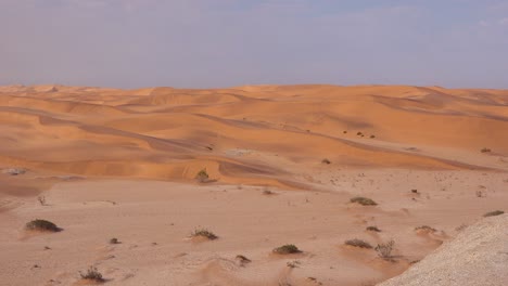 Schwenk-über-Weite-Sanddünen-Der-Namib-Wüste-Namibias-Zu-Einer-Frau,-Die-Auf-Einem-Balkon-Einer-Resort-Lodge-Sitzt