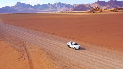 High-aerial-over-a-Toyota-safari-vehicle-heading-across-the-flat-barren-Namib-Desert-in-Namibia-1