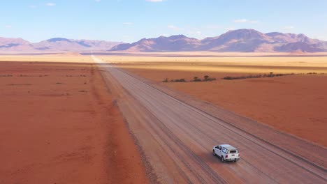 High-aerial-over-a-Toyota-safari-vehicle-heading-across-the-flat-barren-Namib-Desert-in-Namibia-3