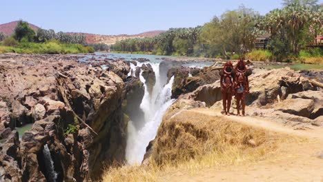 Aerial-reveals-two-Himba-tribal-women-girls-in-front-of-Epupa-waterfalls-on-the-Angola-Namibia-border-Africa-3