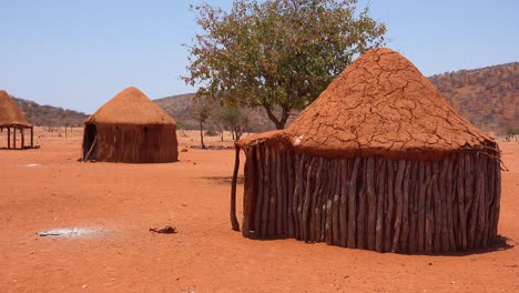 Pequeña-Aldea-Rural-Africana-Pobre-Himba-En-La-Frontera-De-Namibia-Angola-Con-Chozas-De-Barro,-Cabras-Y-Niños
