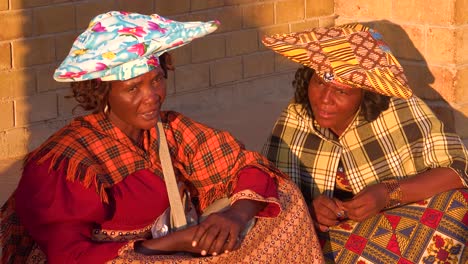Two-Herero-tribal-women-in-large-flat-hats-and-dresses-in-a-market-town-of-Opuwo-Namibia-Africa