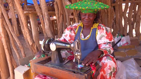 Una-Mujer-Tribal-Africana-Herero-En-Trajes-De-Moda-Brillantes-Opera-Una-Máquina-De-Coser-Antigua-En-Un-Mercado-En-Namibia-África