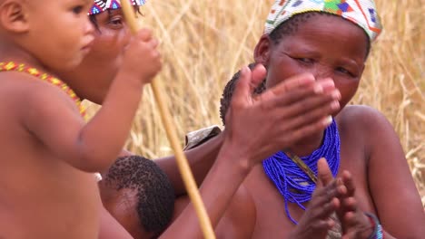 San-Bosquimanos-Africanos,-Mujeres,-Niños-Y-Nativos-Tribales-Se-Sientan-En-Un-Círculo-Cantando-Y-Aplaudiendo-En-Una-Pequeña-Aldea-En-Namibia-3