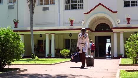 Un-Portero-O-Botones-En-Traje-Colonial-Trae-Equipaje-De-Turista-Desde-El-Elegante-Y-Elegante-Hotel-Victoria-Falls-En-Zimbawbwe