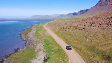 Antena-Sobre-Una-Furgoneta-Negra-Que-Viajaba-Por-Un-Camino-De-Tierra-En-Islandia-Cerca-De-La-Playa-De-Raudisandur-En-Los-Fiordos-Del-Noroeste