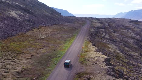 Elevación-De-La-Antena-Sobre-Una-Caravana-Negra-Viajando-Por-Un-Camino-De-Tierra-En-Islandia-En-Los-Fiordos-Del-Noroeste
