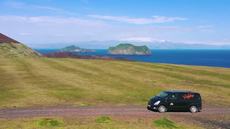 Aerial-over-a-black-camper-van-traveling-on-a-dirt-road-in-Iceland-in-the-Westmann-islands