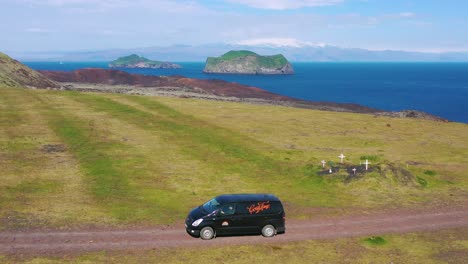 Antenne-über-Einem-Schwarzen-Wohnmobil,-Das-Auf-Einer-Unbefestigten-Straße-In-Island-Auf-Den-Westmann-Inseln-Unterwegs-Ist-1