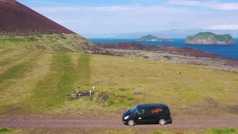 Antena-Sobre-Una-Autocaravana-Negra-Viajando-Por-Un-Camino-De-Tierra-En-Islandia-En-Las-Islas-Westmann-2