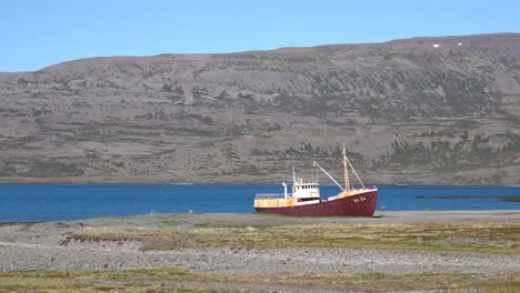 Un-Barco-De-Pesca-Abandonado-Se-Asienta-En-La-Orilla-De-Los-Fiordos-Del-Oeste-Islandia-1