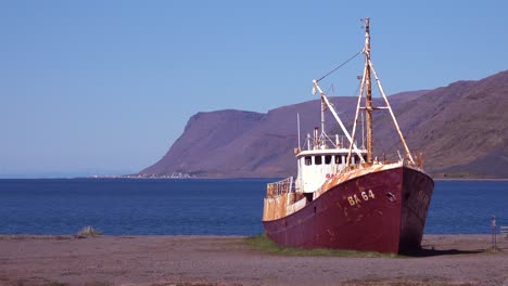 An-abandoned-fishing-boat-sits-on-the-shore-of-the-Westfjords-Iceland-3