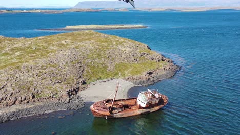 Aerial-over-abandoned-fishing-boat-sitting-on-the-shore-of-the-Westfjords-Iceland-2