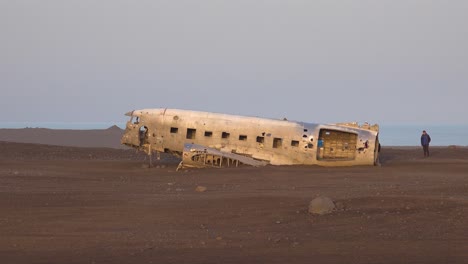 Touristen-Inspizieren-Eine-Abgestürzte-US-Navy-DC-3-Auf-Dem-Schwarzen-Sand-Von-Solheimasandur-Islandand