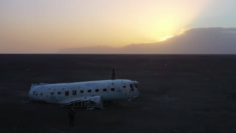 Aerial-man-standing-on-a-crashed-US-Navy-DC-3-on-the-black-sands-of-Solheimasandur-Iceland