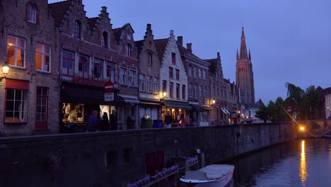Street-of-shops-and-canal-at-night-in-Bruges-Belgium