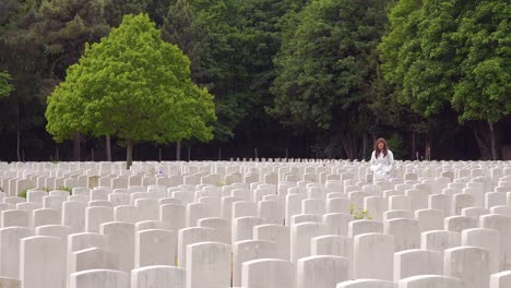 A-woman-in-a-white-coat-looks-at-headstones-of-the-Etaples-France-World-War-cemetery-military-graveyard-3