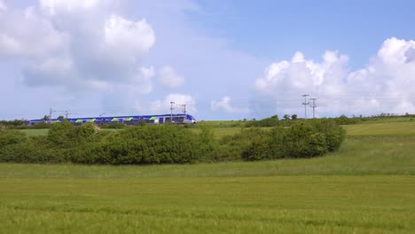 Ein-Elektrischer-Hochgeschwindigkeits-Nahverkehrszug-Fährt-Durch-Die-Landschaft-Der-Normandie-Frankreich