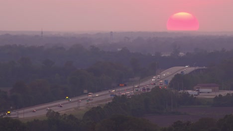 Ein-Riesiger-Ball-Eines-Sonnenuntergangs-Untergehende-Sonne-Hinter-Einem-Stark-Befahrenen-Autobahn--Oder-Autobahnverkehr-In-Der-Nähe-Von-Memphis,-Tennessee