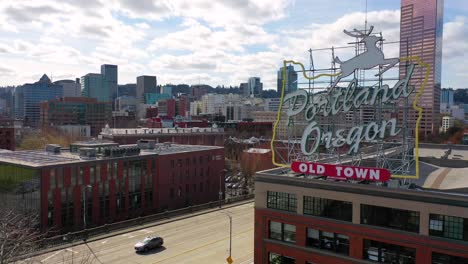 Rising-aerial-reveals-Portland-Oregon-stag-deer-sign-and-downtown-cityscape-and-business-district