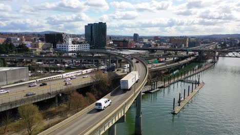 Toma-Aérea-De-Alto-ángulo-De-Tráfico-En-La-Autopista,-Tren-Amtrak-Y-Río-Willamette-En-Portland,-Oregón