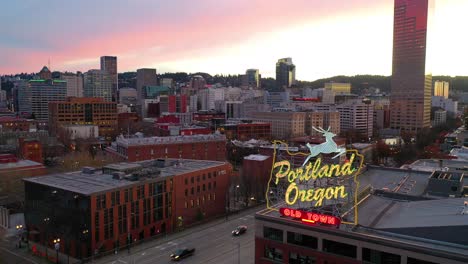 Aerial-past-Portland-Oregon-stag-deer-sign-and-downtown-old-town-cityscape-and-business-district-at-sunset-or-dusk
