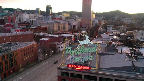 Aerial-around-Portland-Oregon-stag-deer-sign-and-downtown-old-town-cityscape-and-business-district-at-sunset-or-dusk