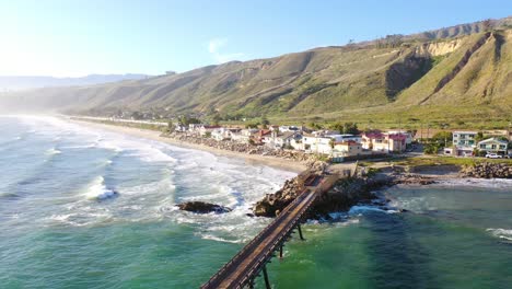 Aerial-over-a-long-oil-pier-and-beach-homes-the-shore-of-Mussel-Shoals-Rincon-Beach-Santa-Barbara-California