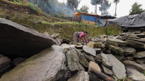 A-Nepalese-woman-piles-rocks-in-front-of-a-makeshift-tent-home-after-becoming-homeless-during-the-devastating-earthquake-there-2