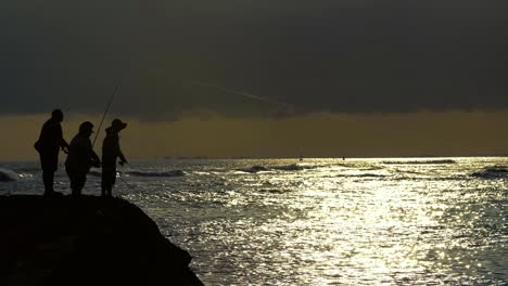 Tres-Pescadores-Emitidos-Durante-La-Atardecer-En-Ala-Moana-Beach-Park-En-Honolulu,-Hawaii