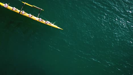 Beautiful-slow-mo-aerial-over-an-outrigger-canoe-paddled-on-blue-water