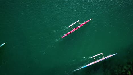 Beautiful-aerial-over-a-red-outrigger-canoe-paddled-on-blue-water