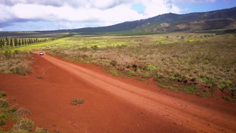 A-silver-Jeep-drives-fast-along-a-red-dirt-road-on-the-island-of-Lanai-in-Hawaii