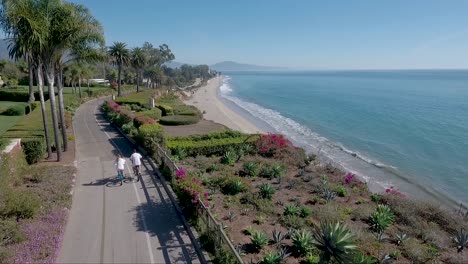Aerial-shot-of-bicyclists-on-a-pathway-above-Butterfly-Beach-in-Montecito-Santa-Barbara-California