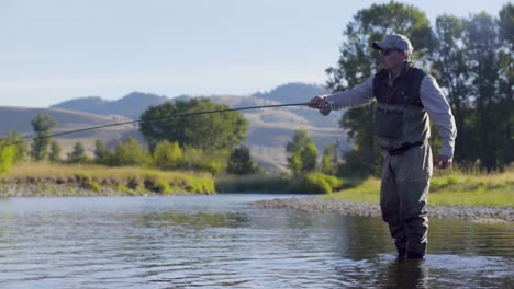 Ein-Fliegenfischer-Wirft-An-Einem-Schönen-Sommermorgen-Nach-Forellen-In-Einem-Fluss-In-Montana-3