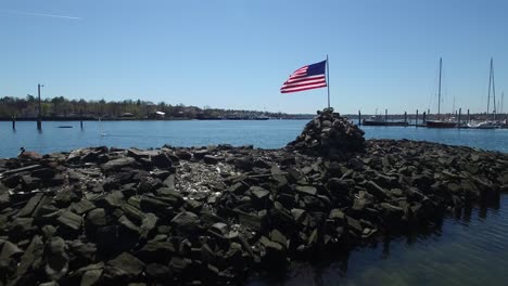 Eine-Antenne-über-Einer-Amerikanischen-Flagge,-Die-Auf-Einer-Insel-In-Einem-See-Weht