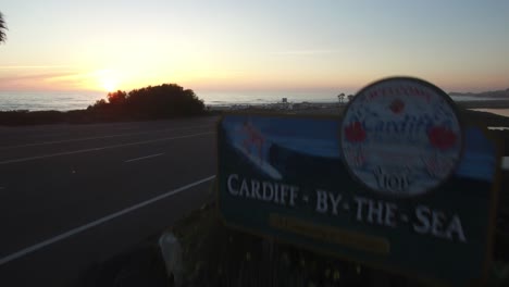 An-aerial-over-a-sign-welcoming-visitors-to-Cardiff-By-The-Sea-in-San-Diego-reveals-the-beach-at-sunset