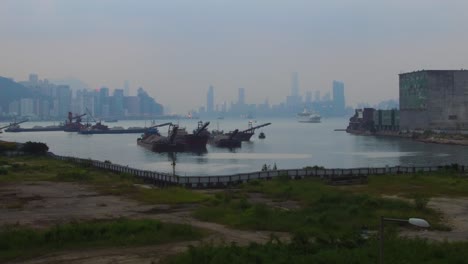 Hafen-Von-Hongkong-In-Nebligen,-Dunstigen-Und-Smoggy-Bedingungen-Mit-Lastkähnen-Und-Booten-Im-Vordergrund