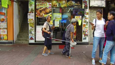 Ein-Armer-Behinderter-Obdachloser-Blinder-Musiker-Wird-Von-Seiner-Frau-Durch-Eine-Straße-In-Hong-Kong-China-Geführt-1