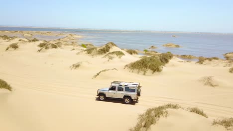 Aerial-over-a-4WD-safari-jeep-vehicle-driving-across-the-sand-dunes-and-Skeleton-Coast-of-Namibia-Africa-1