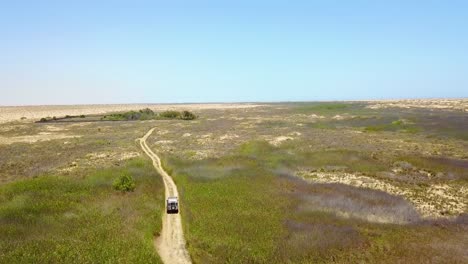 Aerial-of-a-4WD-jeep-vehicle-driving-through-a-grassy-or-marsh-area-on-safari-in-Namibia-Africa-1