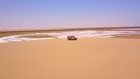 Vista-Aérea-over-a-4WD-safari-vehicle-conduciendo-on-a-colorful-pink-salt-flat-region-in-Namibia-Africa-1