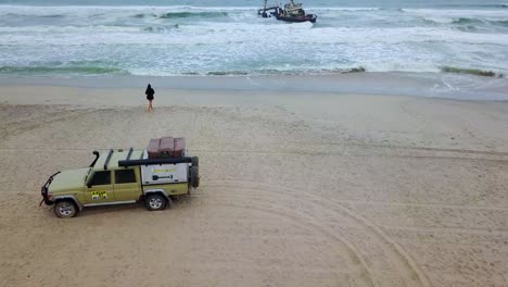 Amazing-aerial-over-a-woman-jogging-or-running-towards-a-shipwreck-along-the-Skeleton-Coast-of-Namibia-Africa