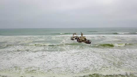 Increíble-Antena-Sobre-Un-Vehículo-De-Safari-4WD-En-Una-Playa-Cerca-De-Un-Naufragio-A-Lo-Largo-De-La-Costa-De-Los-Esqueletos-De-Namibia,-África