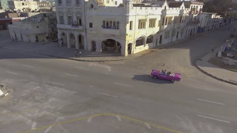 Antena-Drone-De-Un-Grupo-De-Turistas-Que-Viajaban-En-Un-Coche-Antiguo-Clásico-Por-Las-Calles-De-La-Habana,-Cuba