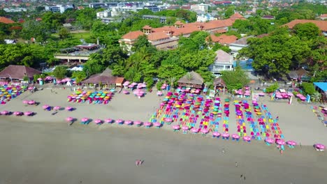 Antena-Sobre-Coloridas-Sombrillas-En-La-Playa-De-Sanur-O-Kuta,-En-La-Costa-De-Bali,-Indonesia