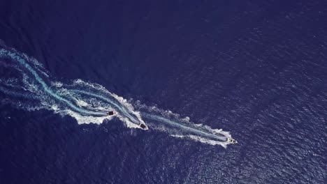 Aerial-looking-straight-down-of-three-speedboats-motor-boats-zig-zagging-on-the-ocean-or-sea-suggesting-water-sports-fun-and-adventure